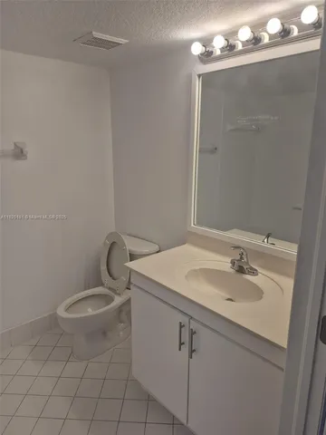 a bathroom with a granite countertop sink a toilet and mirror