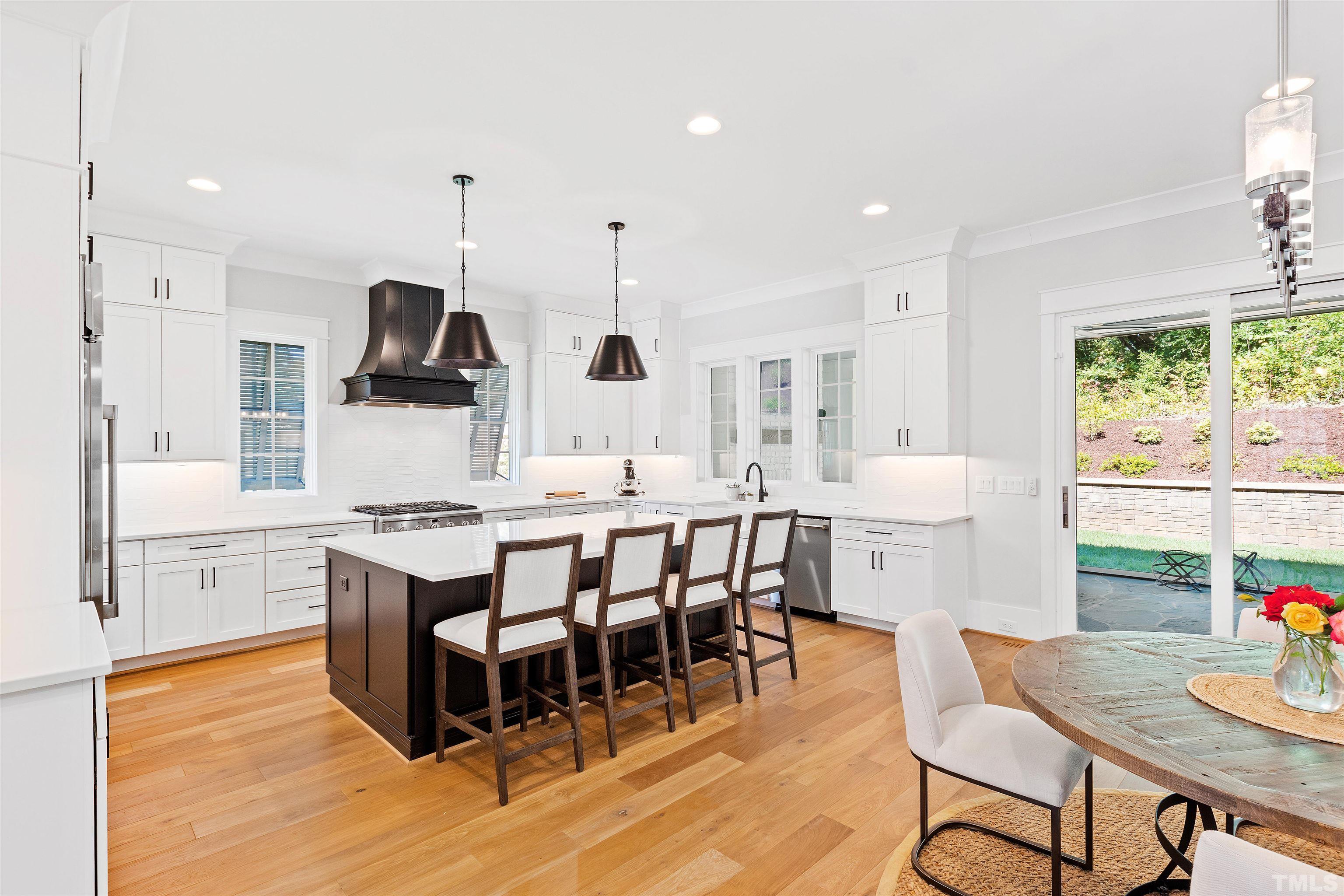 3512 Catalano Drive Raleigh, NC 27607 - Photo 22 of 64 a kitchen with stainless steel appliances kitchen island granite countertop a sink a stove a dining table chairs and view living room