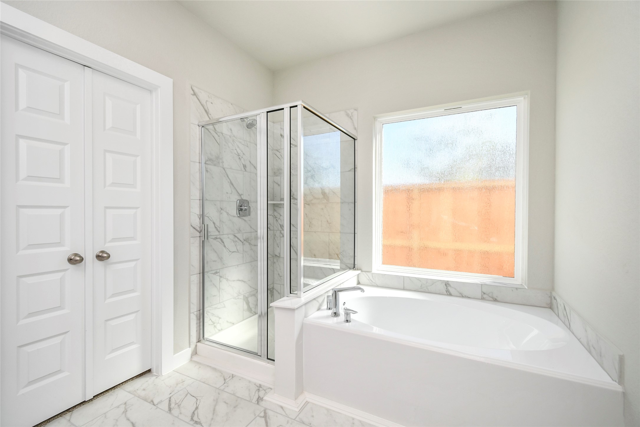 15111 Statice Trail Houston, TX 77044 - Photo 20 of 35 Escape to a spa-like oasis in this primary bathroom. Enjoy a walk-in shower with tile surround, a separate garden tub with custom detailing, and an elegant vanity featuring light countertops, modern hardware, and bright recessed lights. Experience luxury and relaxation in every detail. Sample photo of completed home with similar floor plan. Actual colors and selections may vary.