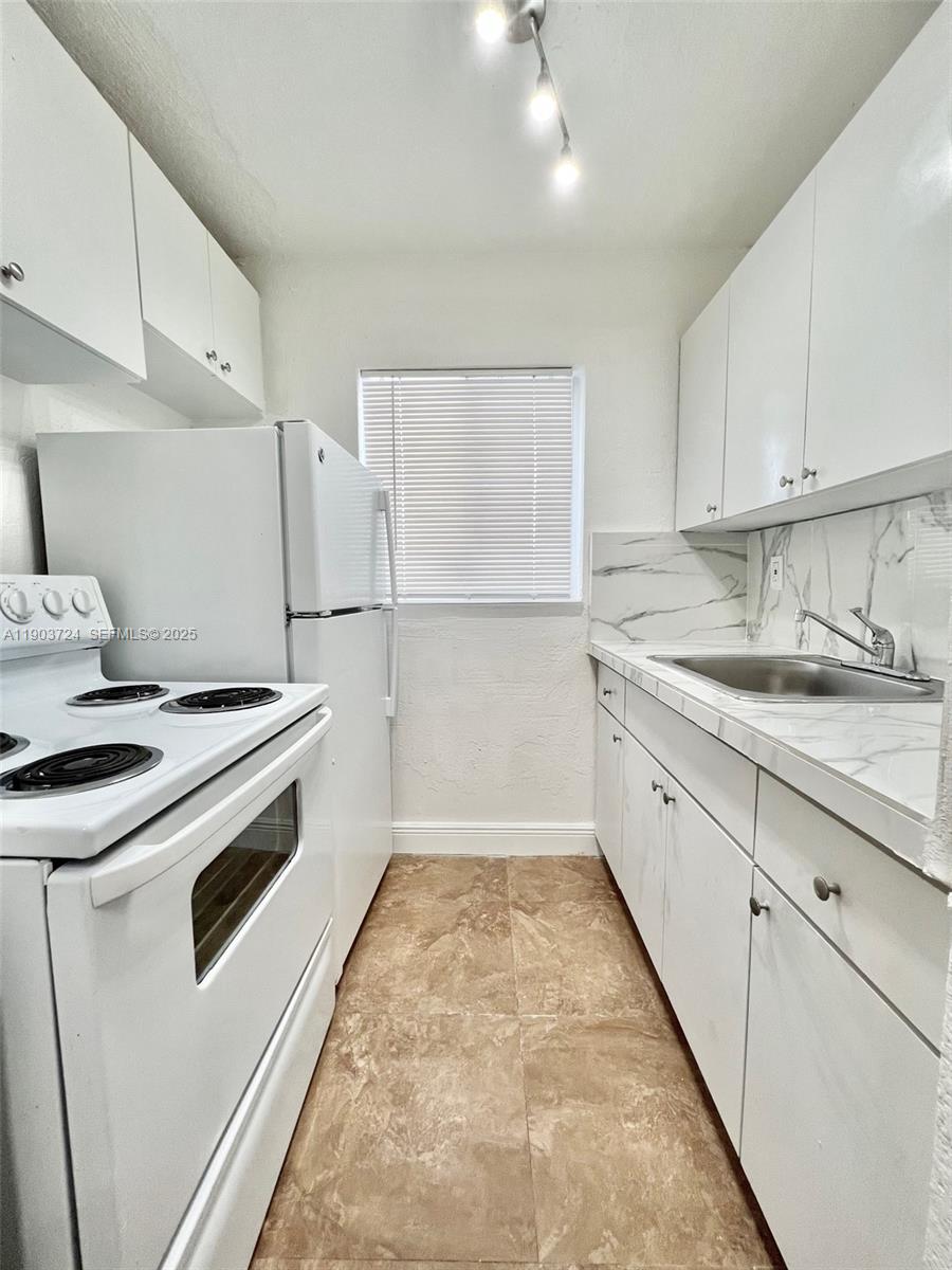 10 Northwest 77th Street, Unit 10 Miami, FL 33150 - Photo 5 of 12 a kitchen with a sink a stove and a refrigerator