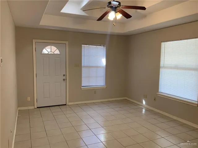a view of an empty room with window and chandelier fan