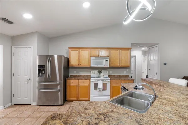 a kitchen with stainless steel appliances granite countertop a sink refrigerator and cabinets