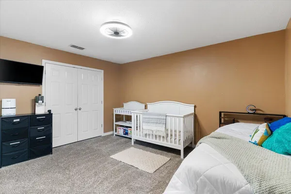 a bedroom with a bed and a flat tv screen on dresser