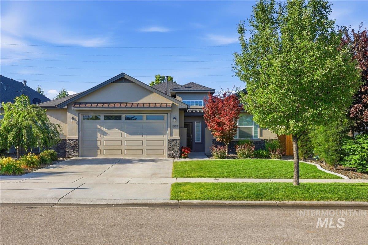 1303 West Brando Street Meridian, ID 83646 - Photo 2 of 49 Single-story residence featuring a two-car garage with transom windows, a concrete driveway, and a stone façade accent