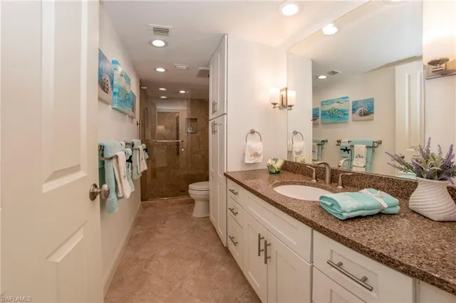 a spacious en suite bathroom with a granite countertop sink and a mirror