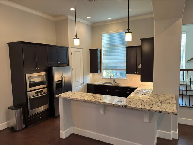 a kitchen with kitchen island granite countertop a sink and refrigerator