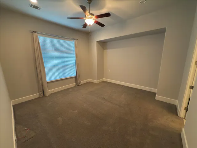 an empty room with a ceiling fan and a window