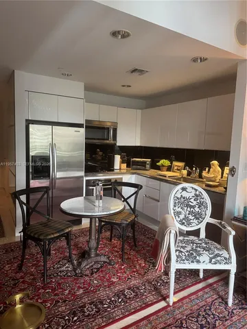 a kitchen with stainless steel appliances a sink a refrigerator a table and chairs