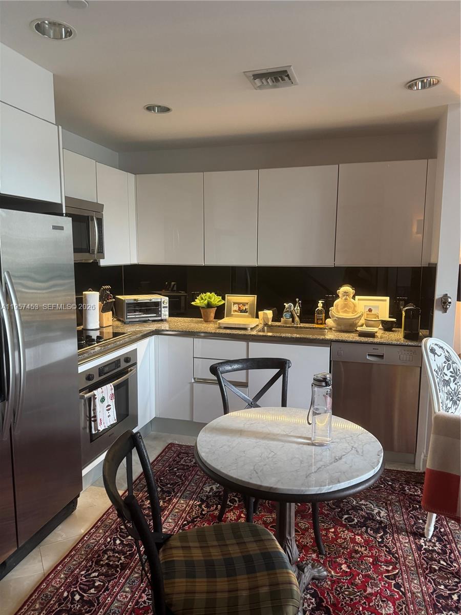 1050 Brickell Avenue, Unit 818 Miami, FL 33131 - Photo 7 of 19 a kitchen with stainless steel appliances a sink a refrigerator a table and chairs