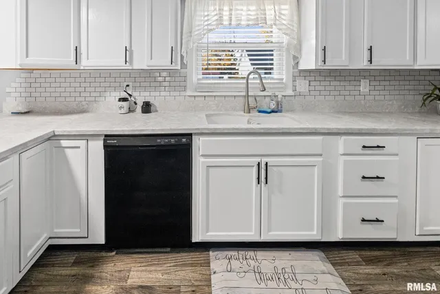 a view of a kitchen with white cabinets and wooden floor