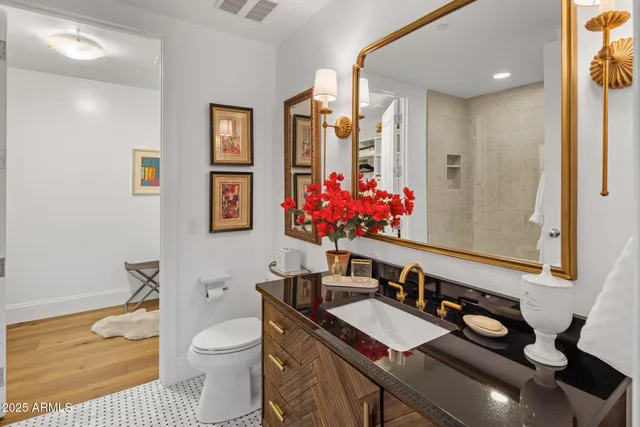 a bathroom with a toilet sink vanity granite and mirror