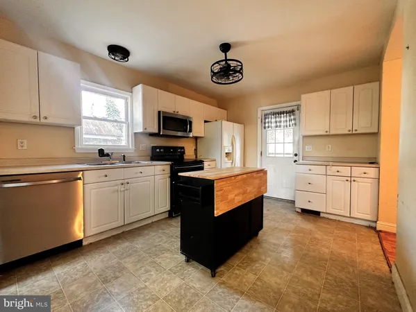 a bedroom with a bed a potted plant on dresser and a wooden floor