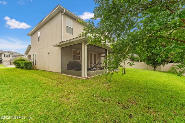 a view of a white house with a big yard and large trees