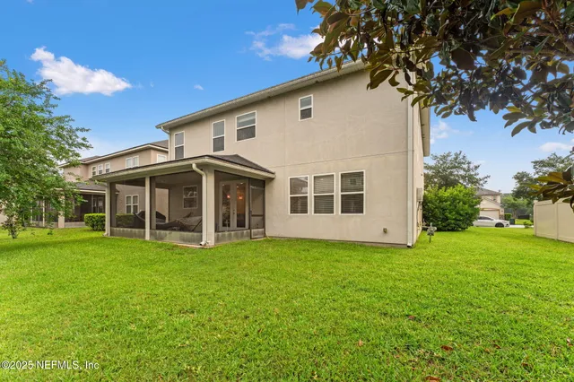 a view of a white house with a big yard and large trees