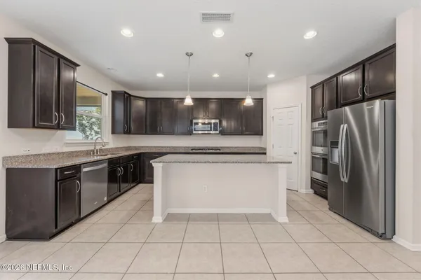a large kitchen with a large counter top stainless steel appliances and cabinets