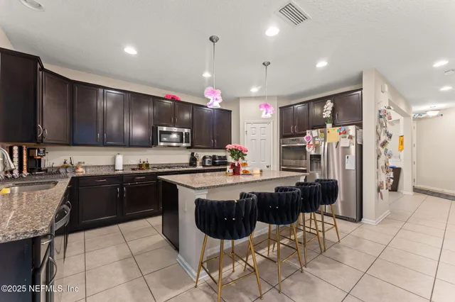 a kitchen with stainless steel appliances granite countertop a stove top oven a sink dishwasher a dining table and chairs with wooden floor