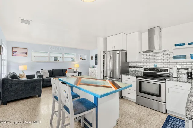 a kitchen with stainless steel appliances a stove a sink refrigerator and a couch