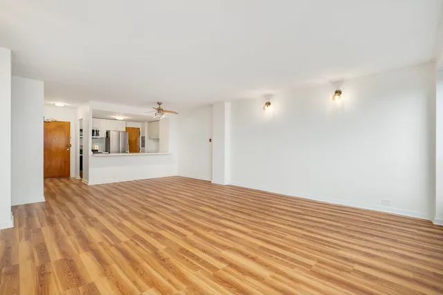 a view of a livingroom with wooden floor and kitchen space