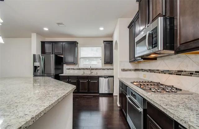 a kitchen with stainless steel appliances granite countertop a sink stove and refrigerator