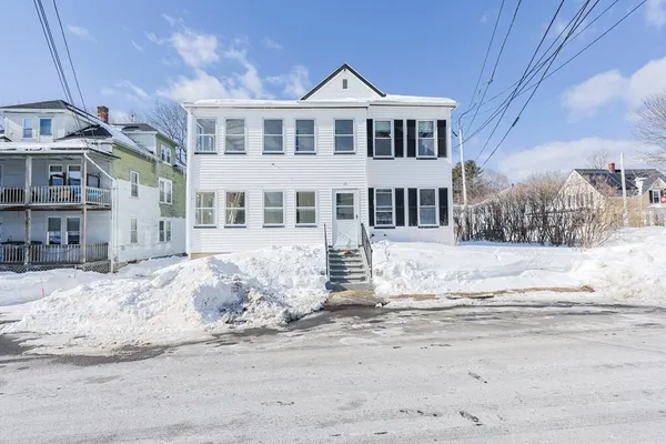 a front view of a house with a yard covered in snow