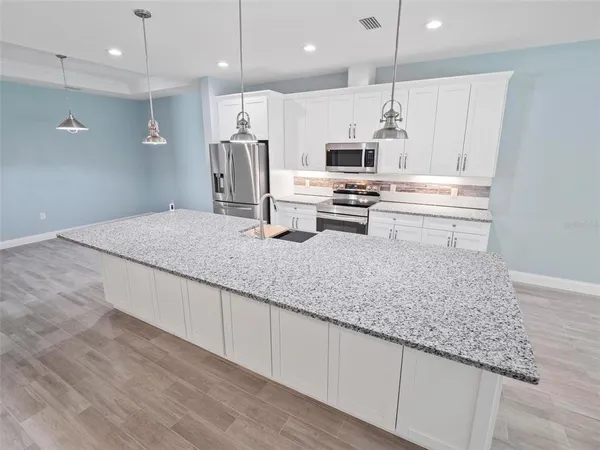 a kitchen with stainless steel appliances kitchen island granite countertop a stove a sink and a refrigerator