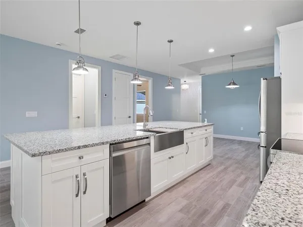 a large kitchen with granite countertop a sink and white cabinets