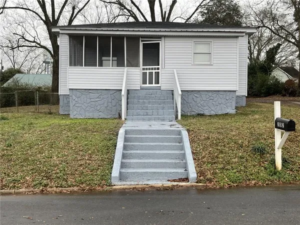 a front view of house with yard and trees in the background