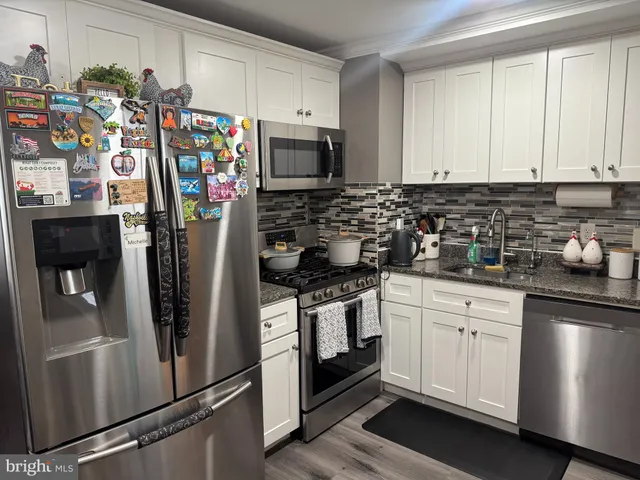 a kitchen with stainless steel appliances granite countertop a refrigerator a stove and a sink