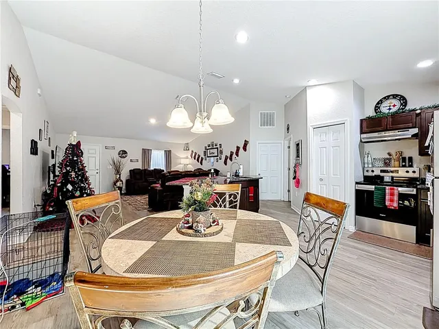 a dining room with furniture a chandelier and kitchen view