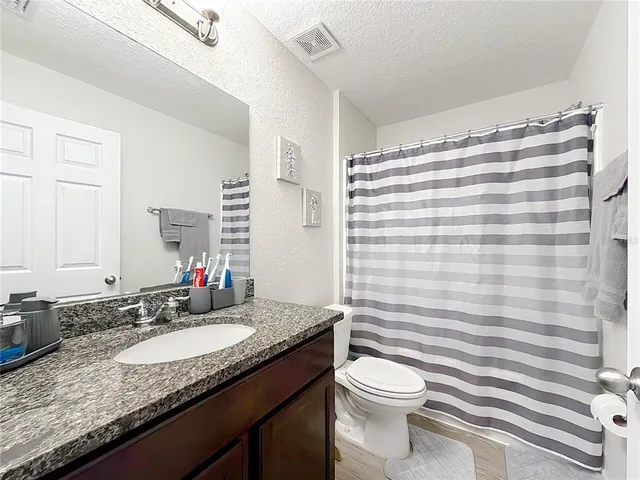 a bathroom with a granite countertop sink a mirror and a toilet