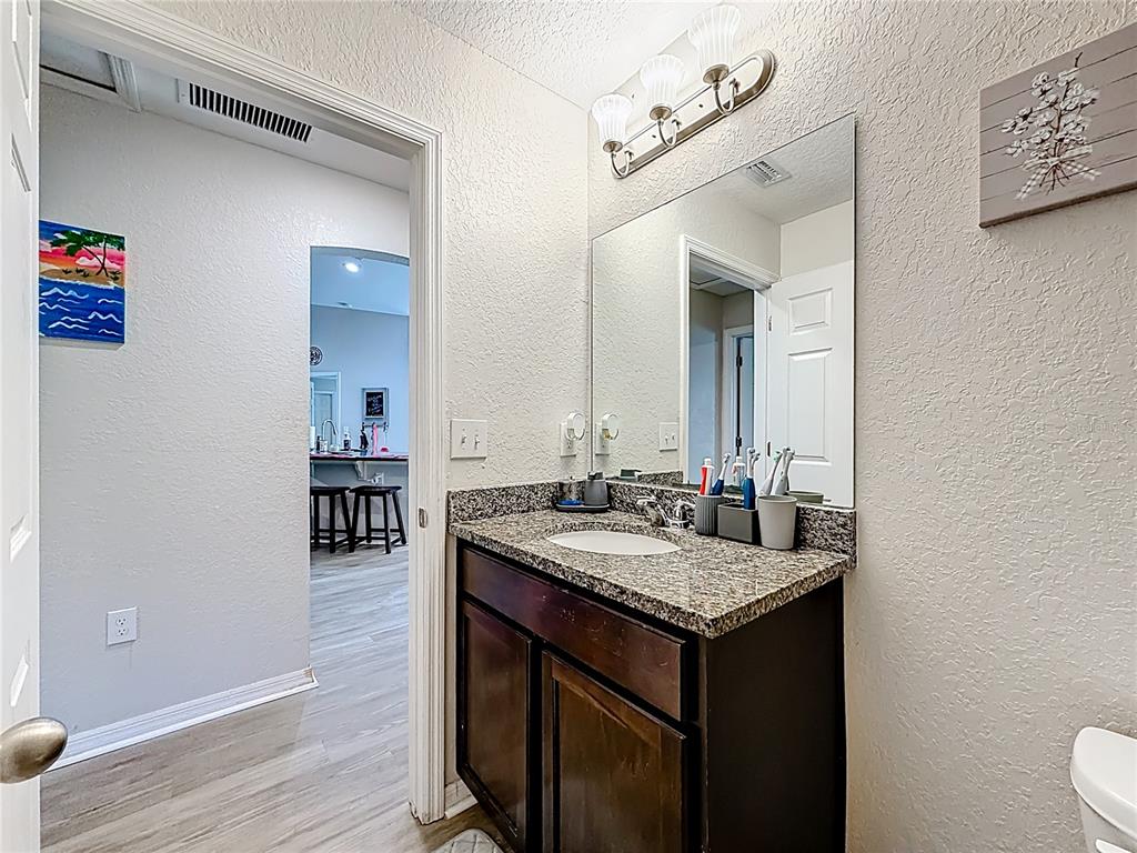 6188 East Seneca Street Inverness, FL 34452 - Photo 20 of 32 a bathroom with a granite countertop sink a mirror and a toilet