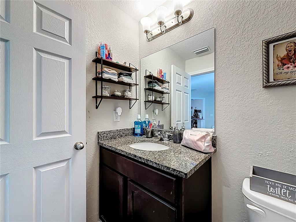 6188 East Seneca Street Inverness, FL 34452 - Photo 26 of 32 a bathroom with a granite countertop sink a toilet and a mirror