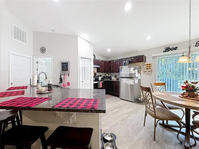 a kitchen with a dining table chairs and refrigerator