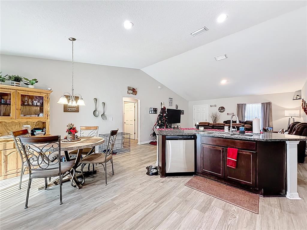 6188 East Seneca Street Inverness, FL 34452 - Photo 9 of 32 a kitchen with stainless steel appliances kitchen island granite countertop a table chairs and a refrigerator
