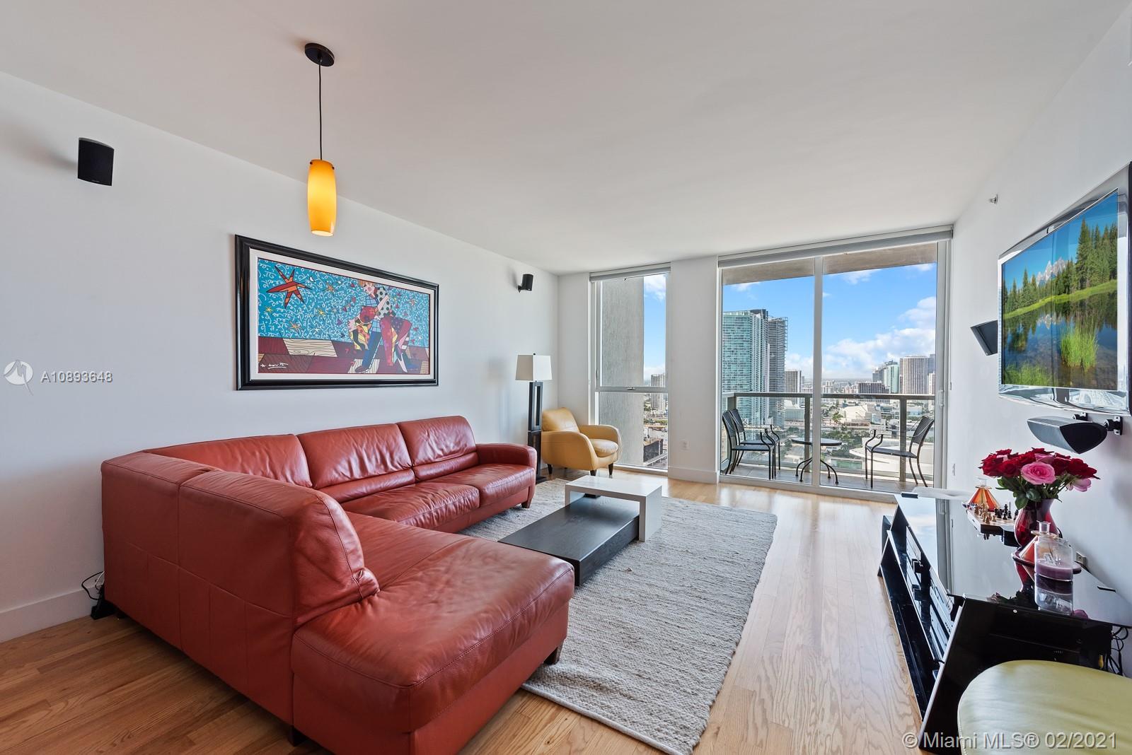 244 Biscayne Boulevard, Unit 3406 Miami, FL 33132 - Photo 2 of 20 a living room with furniture a flat screen tv and a floor to ceiling window