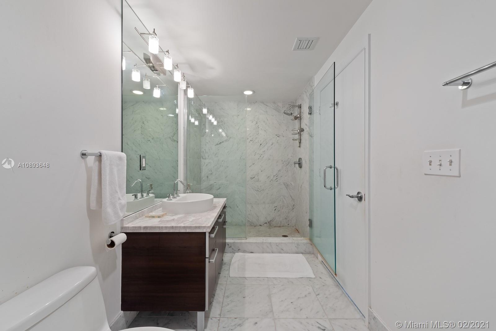 244 Biscayne Boulevard, Unit 3406 Miami, FL 33132 - Photo 10 of 20 a bathroom with a granite countertop sink a toilet a shower and a mirror