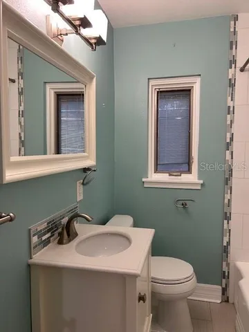 a bathroom with a toilet sink and mirror
