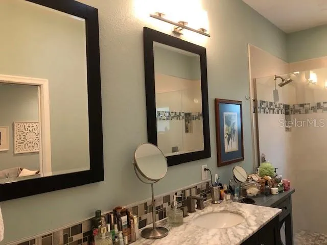a bathroom with a granite countertop sink a mirror and a shower