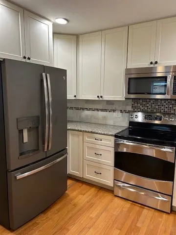 a kitchen with granite countertop a refrigerator stove and microwave