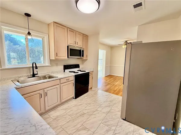 a kitchen with stainless steel appliances granite countertop a sink a stove and a refrigerator