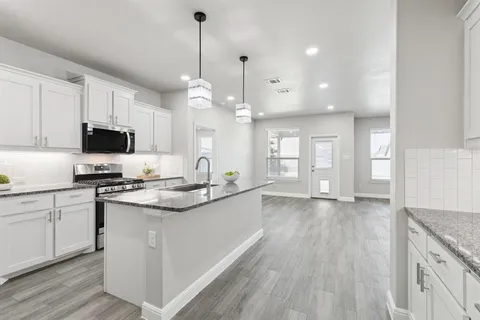 a kitchen with stainless steel appliances granite countertop a sink a stove and a wooden floors
