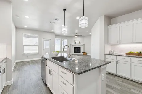 a kitchen with stainless steel appliances granite countertop a sink a stove and a wooden floors