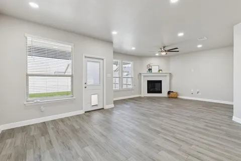 an empty room with wooden floor fireplace and windows