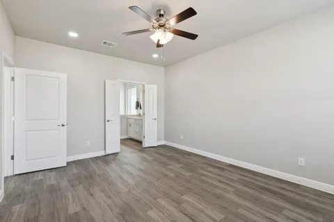 an empty room with wooden floor and a ceiling fan
