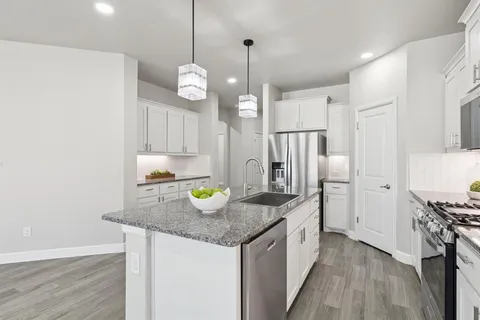 a kitchen with a refrigerator a sink and wooden floor