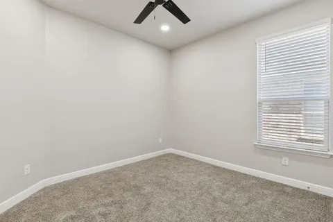 an empty room with a window and a fan