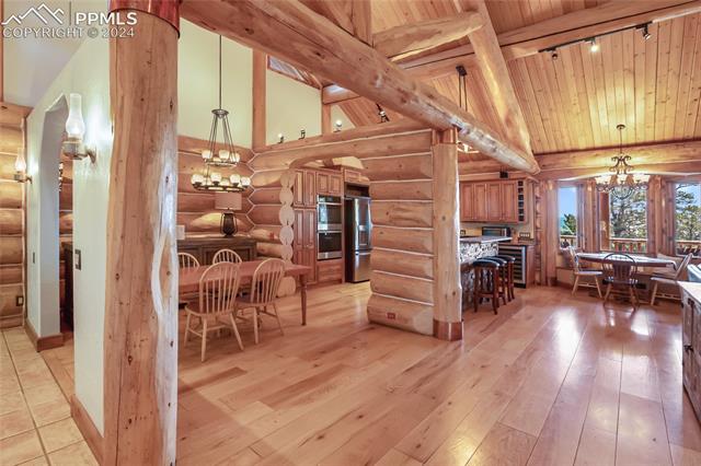 616 Summit Road Hartsel, CO 80449 - Photo 20 of 50 Kitchen with light wood-type flooring, an inviting chandelier, rustic walls, wood ceiling, and appliances with stainless steel finishes