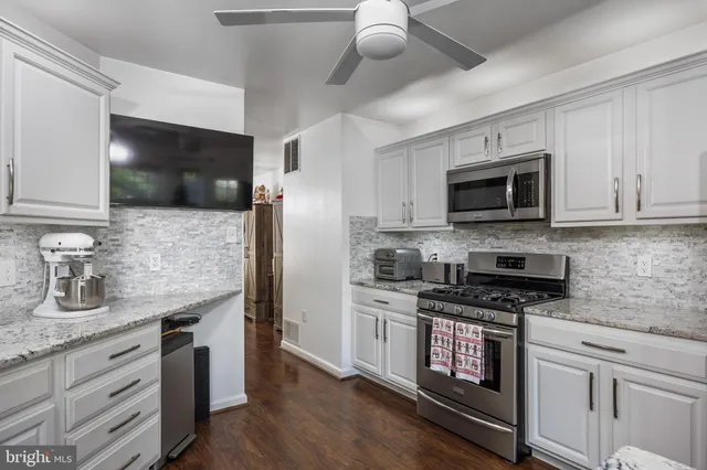 a kitchen with stainless steel appliances granite countertop a stove a microwave a refrigerator a sink and dishwasher with wooden floor