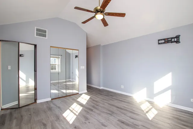 a view of empty room with wooden floor and fan