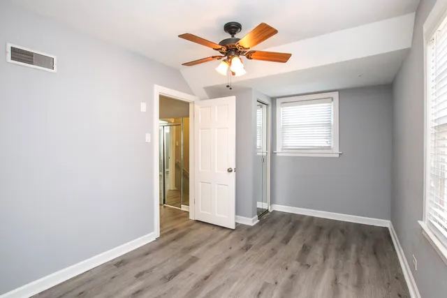 an empty room with wooden floor window and ceiling fan
